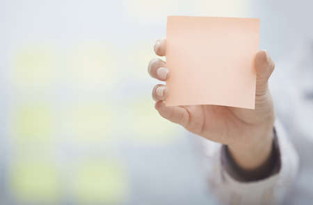 Woman holding sticky note with empty spaceの写真素材