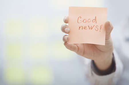 Woman holding sticky note with Good news textの写真素材