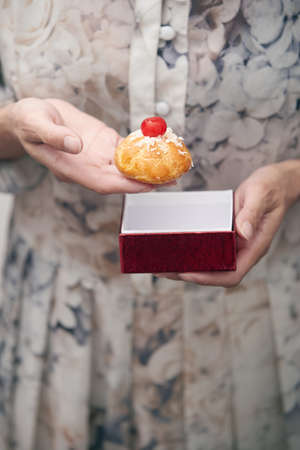 Woman holding eclair and red box. Vertical photoの写真素材