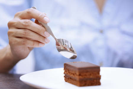 Hand of woman eating chocolate cakeの写真素材