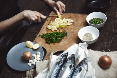 Woman cutting lemon for fish stuffingの写真素材