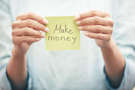 Woman holding sticky note with Make money textの写真素材