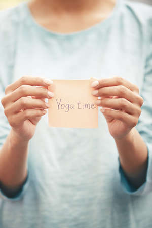 Woman holds adhesive note with Yoga time textの写真素材