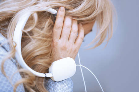 Blond woman listening music via headphonesの写真素材