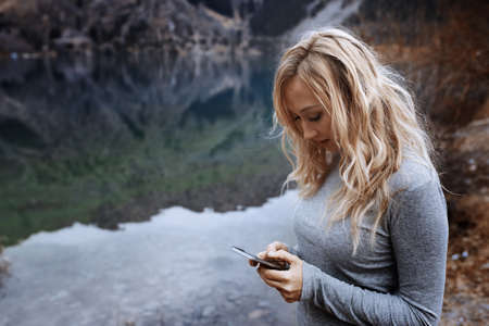 Woman using smartphone at the mountain lake