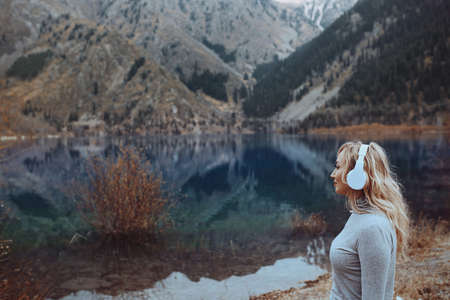 Woman wearing wireless headphones at the mountain lakeの写真素材