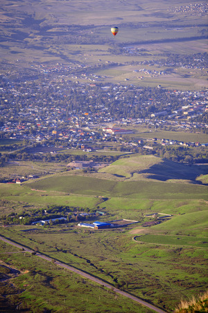 Hot air balloon above the green field and villagesの写真素材