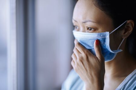 Woman staying at home wearing protective surgical maskの写真素材