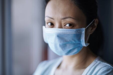 Woman staying at home wearing protective surgical maskの写真素材