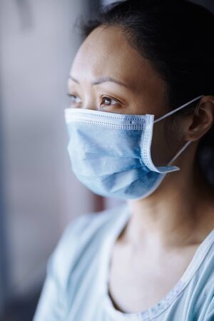 Woman staying at home wearing protective surgical maskの写真素材