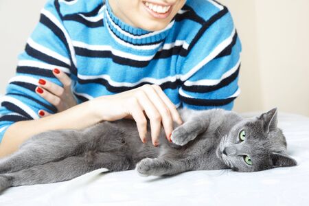 Cat pampering indoors and smiling woman. Shallow depth of fieldの写真素材