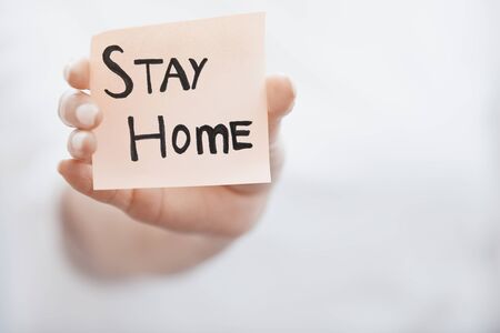 Hand holding sticky note with Stay Home textの写真素材