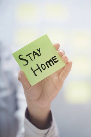 Hands holding sticky note with Stay Home textの写真素材