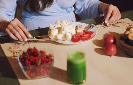 Vegetarian woman sitting at the table and eating healthy foodの写真素材