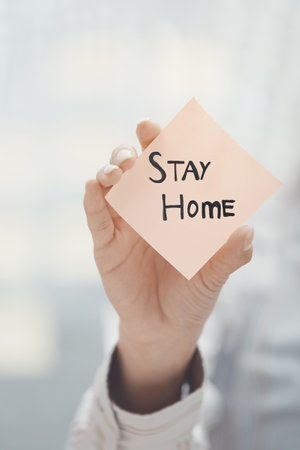 Hand holding sticky note with Stay Home textの写真素材
