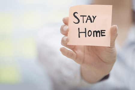 Hands holding sticky note with Stay Home textの写真素材