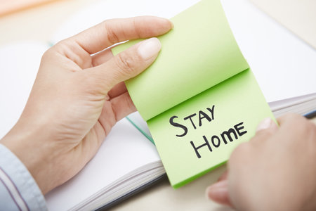 Hands holding sticky note with Stay Home textの写真素材