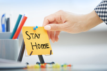 Human hand holding adhesive note with Stay Home orderの写真素材