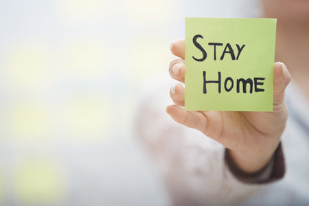 Hand holding sticky note with Stay Home textの写真素材