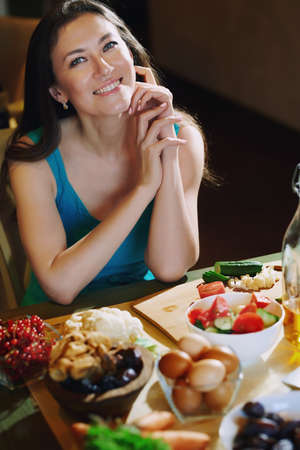Woman sitting at the table with vegetablesの写真素材