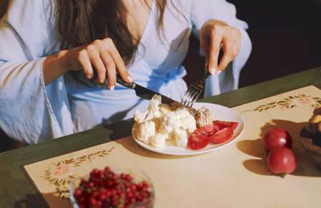 Vegetarian woman sitting at the table and eating healthy foodの写真素材