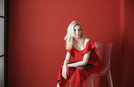 Young adult woman sitting on a chair and holding laptopの写真素材