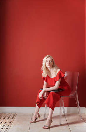 Young adult woman sitting on a chair and holding laptopの写真素材