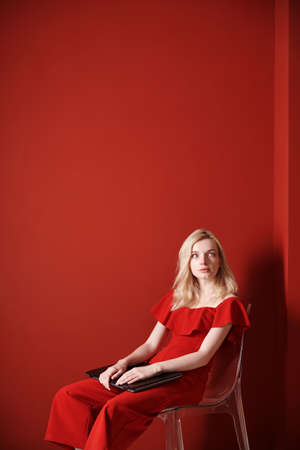 Young adult woman sitting on a chair and holding laptopの写真素材