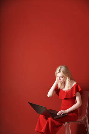 Young adult woman sitting on a chair and working on laptopの写真素材
