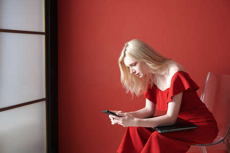 Young adult woman using smartphone and holding laptopの写真素材