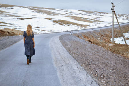 Woman walking along the rural highwayの写真素材