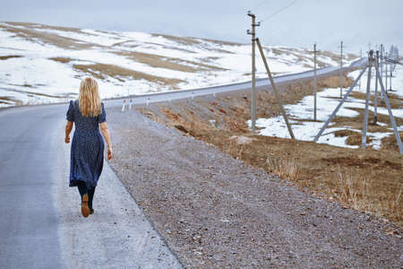 Woman walking along the rural highwayの写真素材