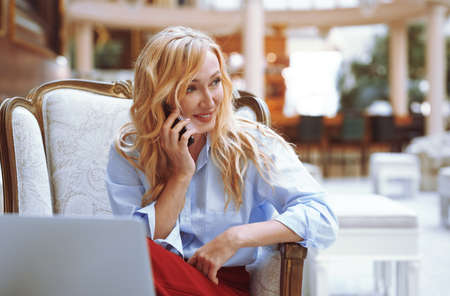 Businesswoman calling via smartphone in the modern bank lobbyの写真素材