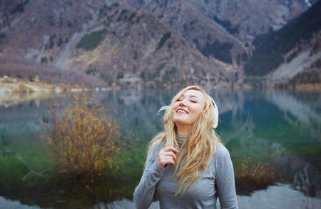Woman wearing wireless headphones at the mountain lakeの写真素材