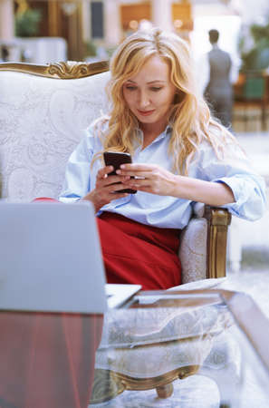 Businesswoman using smartphone in the modern bank lobbyの写真素材
