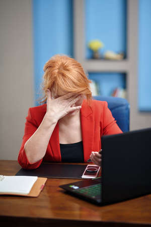 Overworked and stressed businesswoman working on laptop at the officeの写真素材