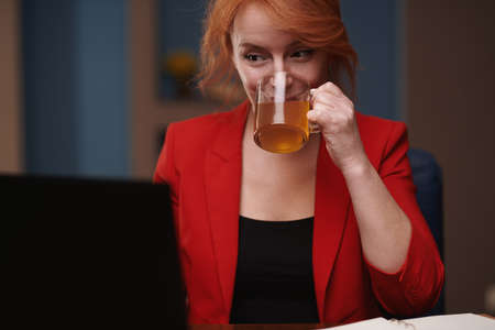 Businesswoman drinking tea while working on laptop at the officeの写真素材