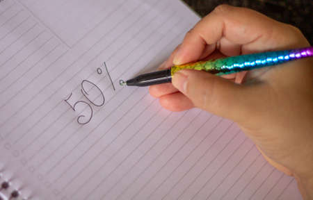 50 percent handwritten, female hand holding a colored pen in the shape of a mermaid's tail, in a...