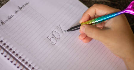 50 percent handwritten, female hand holding a colored pen in the shape of a mermaid's tail, in a...