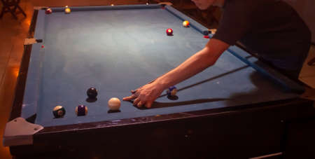 Young man playing snooker in a pool club. Selective focus.