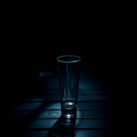 Glass on a wooden table in a dark room. Selective focus.の写真素材