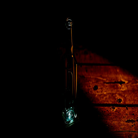 An empty bottle on a wooden table with a dark background.の写真素材
