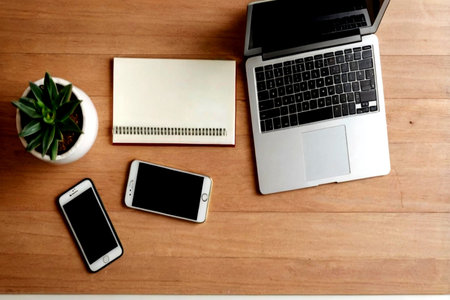 Office desk table with laptop, smartphone, notebook and plant. Top view with copy space