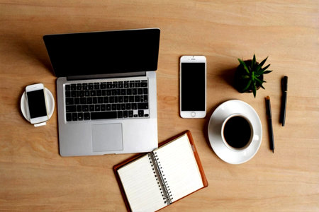 Top view of office desk with laptop, smartphone, notebook and coffee cup