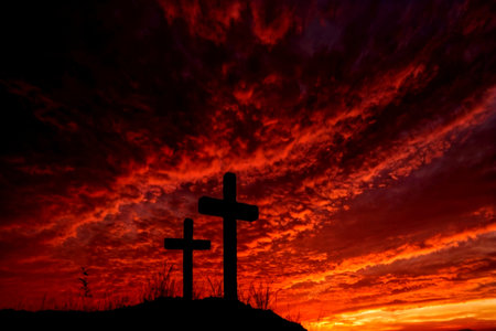 Cross silhouette at sunset with red sky and clouds. Christian symbols.