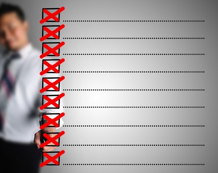 Business man drwing symbol of wrong  in checkbox listの写真素材