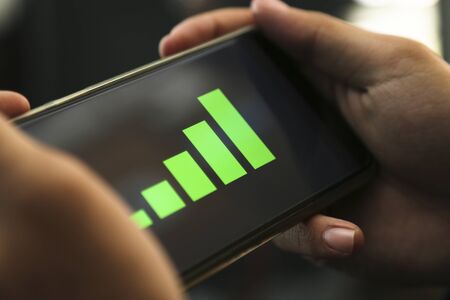 hands showing profit graph on a smart phoneの写真素材