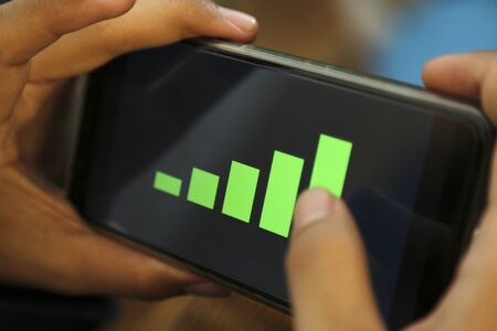 hands showing profit graph on a smart phoneの写真素材