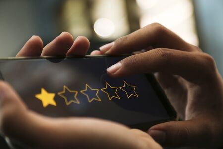 attractive hands giving one star rating on a smart phoneの写真素材