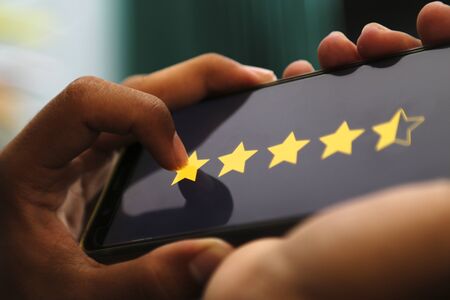 attractive hands giving four point five stars rating on a smart phoneの写真素材